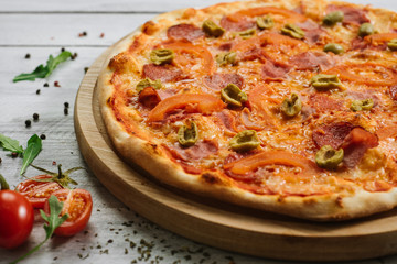 Tasty pizza Chachatore with mozzarella, salami and olives on the white wooden background