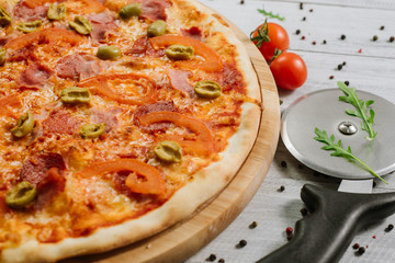 Tasty pizza Chachatore with mozzarella, salami and olives on the white wooden background