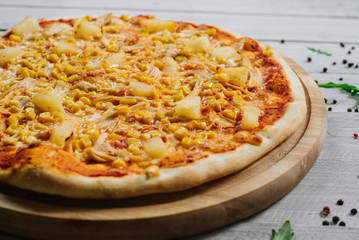 Pizza Americana with mozzarella, chicken fillet, pineapple and corn on the wooden background