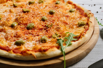 Tasty fresh pizza Margarita with mozzarella and olives on the white wooden background