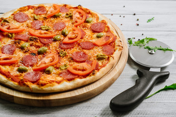Delicious pizza Neapolitana with tomato sauce, mozzarella and ham on the white wooden background