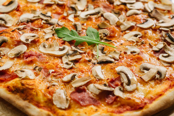 Tasty pizza Caprizzioza with tomato sauce, ham and champignons on the white wooden background