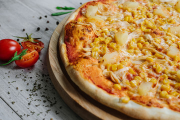 Pizza Americana with mozzarella, chicken fillet, pineapple and corn on the wooden background