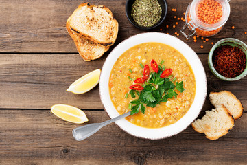 Lentil soup with  bread in a ceramic bowl on a wooden background .