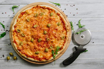 Tasty fresh pizza Margarita with mozzarella and olives on the white wooden background