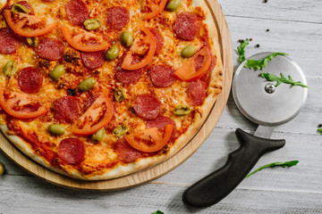 Delicious pizza Neapolitana with tomato sauce, mozzarella and ham on the white wooden background