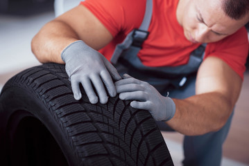 Mechanic holding a tire tire at the repair garage. replacement of winter and summer tires © standret