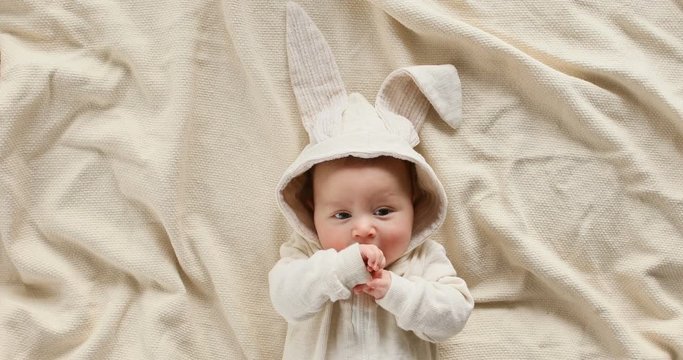 Cute baby smiling and looking in the camera close up. Little kid in Easter bunny costume, top view