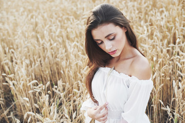 Beautiful girl in a field of wheat in a white dress, a perfect picture in the style lifestyle