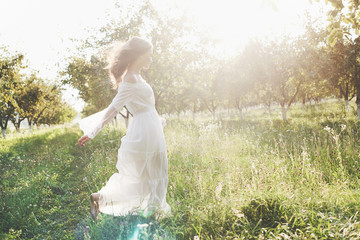 Beautiful young woman wearing elegant white dress and enjoying beautiful sunny afternoon in a...