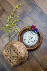 Wooden plate with jasmine rice and black sesame seeds on a wooden background