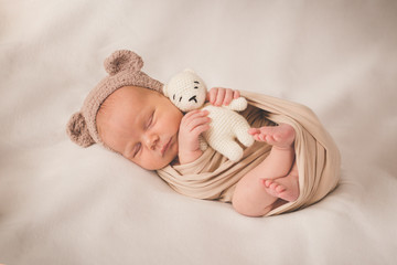 Newborn sleeping boy with a toy in a hat with ears