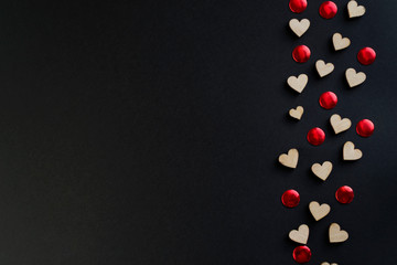 Valentines day background with red hearts on black table, top view.