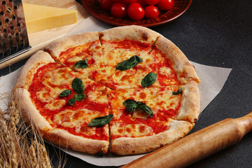 Pizza Margarita on black stone background, top view with tomatoes cheese and cherry and basil. Web banner, menu for restaurant or cafe, recipe concept. 