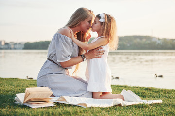 Happy young mother with a playful daughter in a park near the water