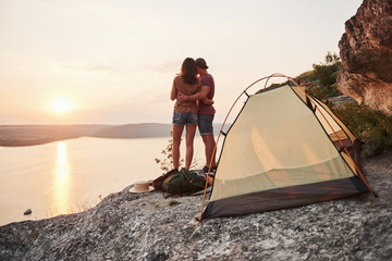 Fototapeta premium Photo of happy near tent with a view of lake during hiking trip. Travel Lifestyle adventure vacations concept