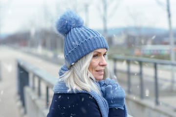 Pretty blond woman standing in falling winter snow
