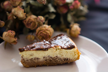 Cheesecake with chocolate and dried rose flowers on black background