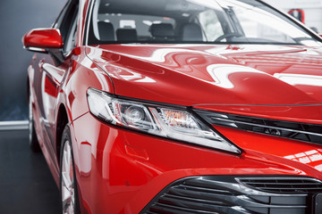 Obraz na płótnie Canvas Headlights of the new red car, in the car dealership.