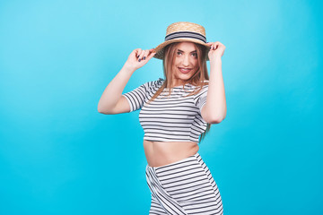 Obraz na płótnie Canvas Attractive girl in a white and black stripes, hat, sunglasses, emotionally opened mouth on a bright blue background with a perfect body. Isolated. Studio shot
