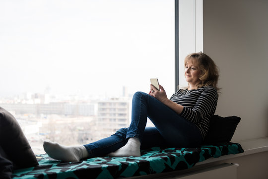 Smiling relaxed lady using smartphone