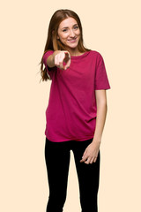 Young redhead girl points finger at you with a confident expression on isolated yellow background