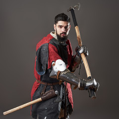 Medieval knight on grey background. Portrait of brutal dirty face warrior with chain mail armour...