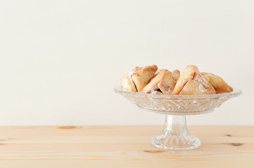 Purim celebration concept (jewish carnival holiday). Traditional hamantaschen cookies over wooden table.