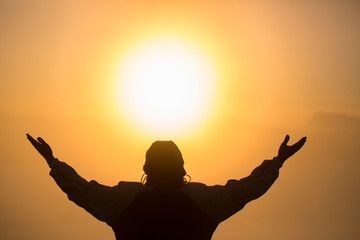 Man praying at sunset mountains raised hands Travel Lifestyle spiritual relaxation emotional...