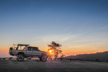 sunset at Huai Nam Dang National Park, beautiful silhouette of a 4x4 truck parking on the road with colorful red light in the sky background, Huai Nam Dang in Chiang Mai, northern of Thailand.