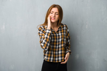 Young redhead girl over grunge wall with toothache