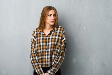 Fototapeta premium Young redhead girl over grunge wall feeling upset