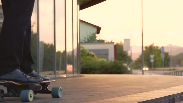 SLOW MOTION, CLOSE UP, LOW ANGLE: Unrecognizable businessman longboarding through city on sunny evening. Active corporate professional riding his high tech electric skateboard after a long day at work