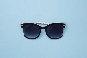 Women`s sunglasses are on a blue background in the center. Horizontal paper texture.