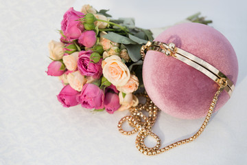 Round gently pink clutch and bridal bouquet of white and pink roses on a white background. The original women's handbag.