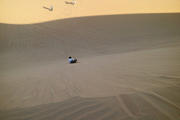 Fototapeta na wymiar Young Man Sand Boarding Down the Sand Dune of Huacachina Desert, Ica Region of Peru, South America