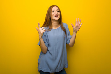 Young redhead girl over yellow wall background counting seven with fingers