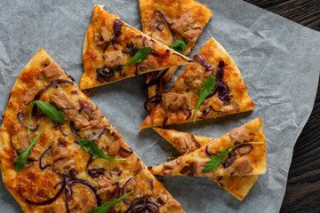Homemade tuna and mozzarella pizza on wooden background.
