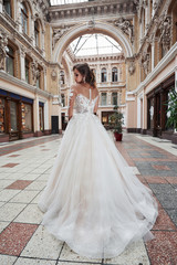 Beautiful, elegant bride with a perfect wedding dress, poses around beautiful architecture.