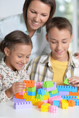 Portrait of mother and children playing with colorful plastic blocks together