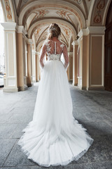 Beautiful, elegant bride with a perfect wedding dress, poses around beautiful architecture