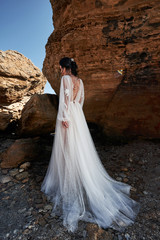 Portrait of a girl in a wedding gorgeous dress posing a photographer on the beach.