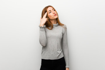 Redhead girl over white wall with problems making suicide gesture