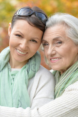 Portrait of smiling senior woman with adult daughter in autumnal park