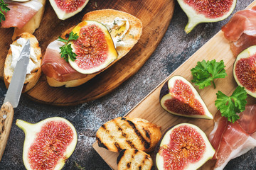 Prosciutto with figs . Fresh figs with ham and cheese on a grilled toast, rustic background. Appetizing snack. Top view,toned photo