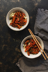 Asian udon noodles with chicken teriyaki sauce on a dark background. Top view, flat lay, copy space.