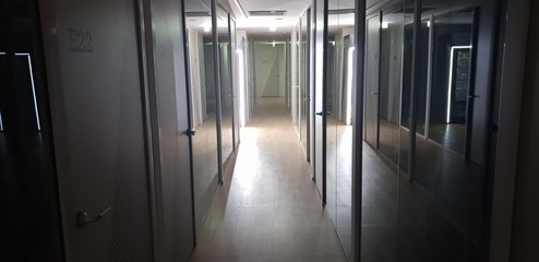 Long corridor with glass wall and white door in the night