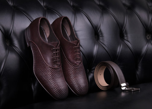 Men's shoes and belt. Elegant men's leather shoes and belt on a black leather sofa.