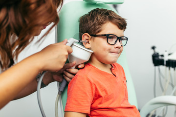 Young boy at medical examination or checkup in otolaryngologist's office. Ear irrigation and earwax...