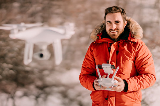 Close upt portrait of young adult, caucasian male operating drone, flying drone with remote control for aerial video and photography